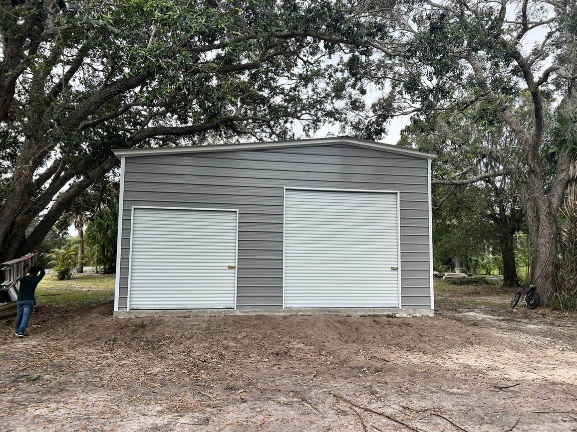 Finished gray metal garage with two roll-up doors on a concrete slab