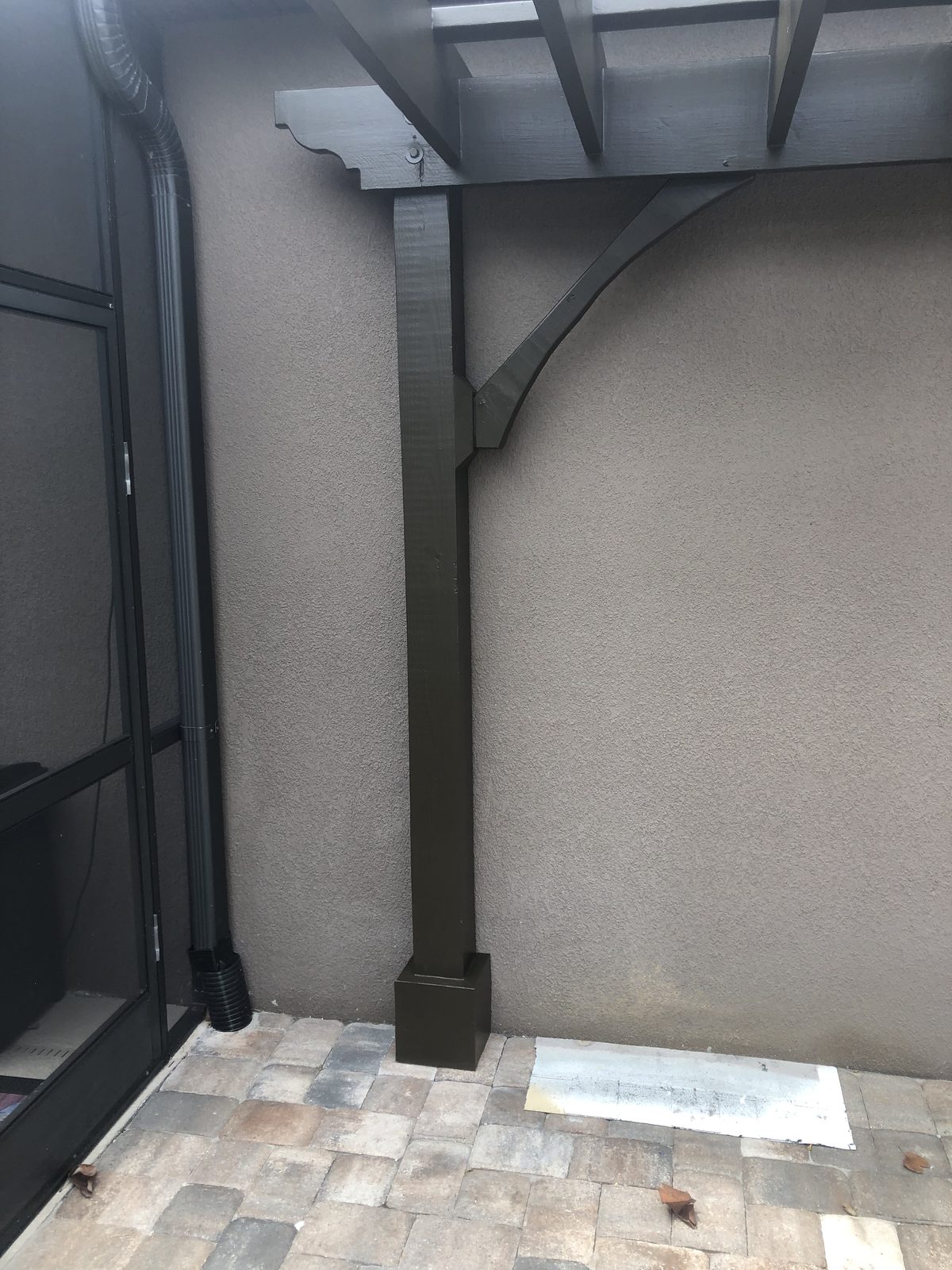 Pergola post with a curved corbel bracket fastened to a stucco wall