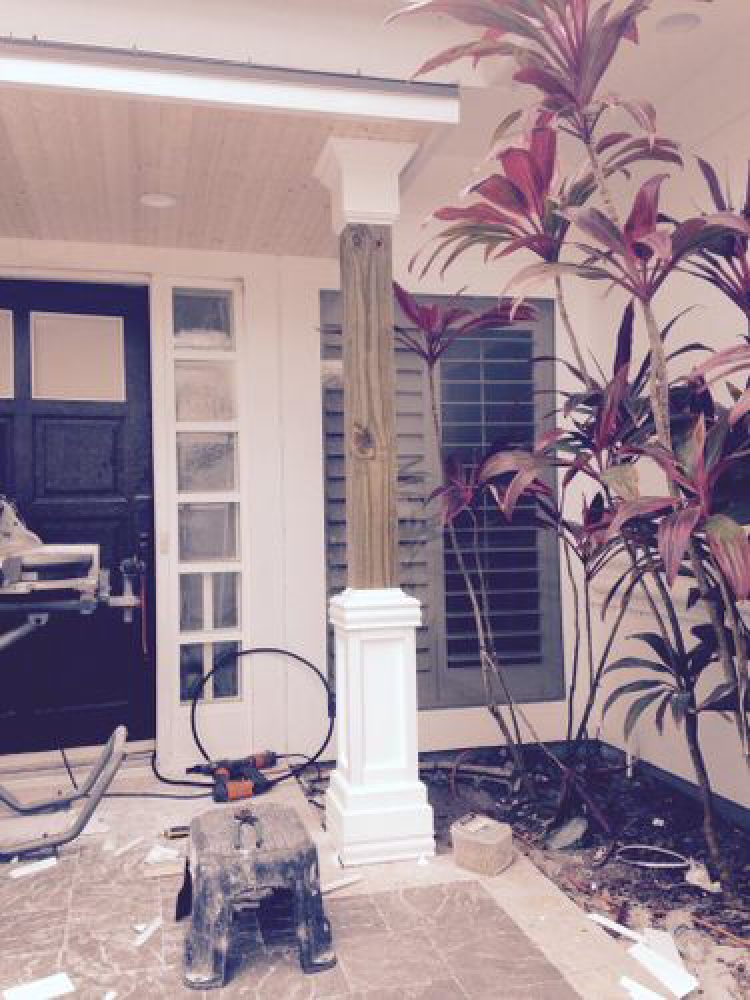 Porch post being wrapped with a paneled column base and cap