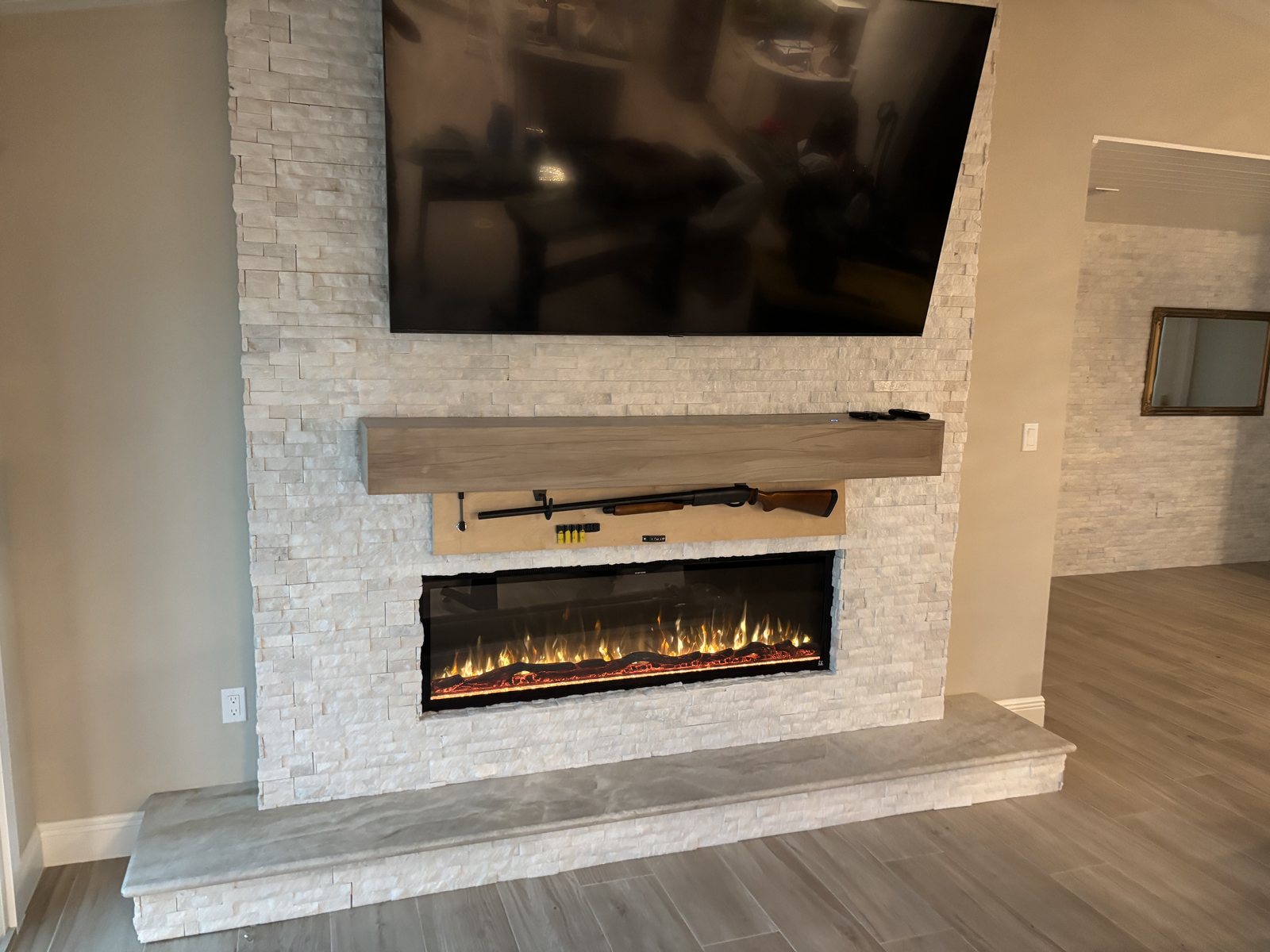 The same mantel opened to reveal a concealed compartment holding a long gun and ready ammunition