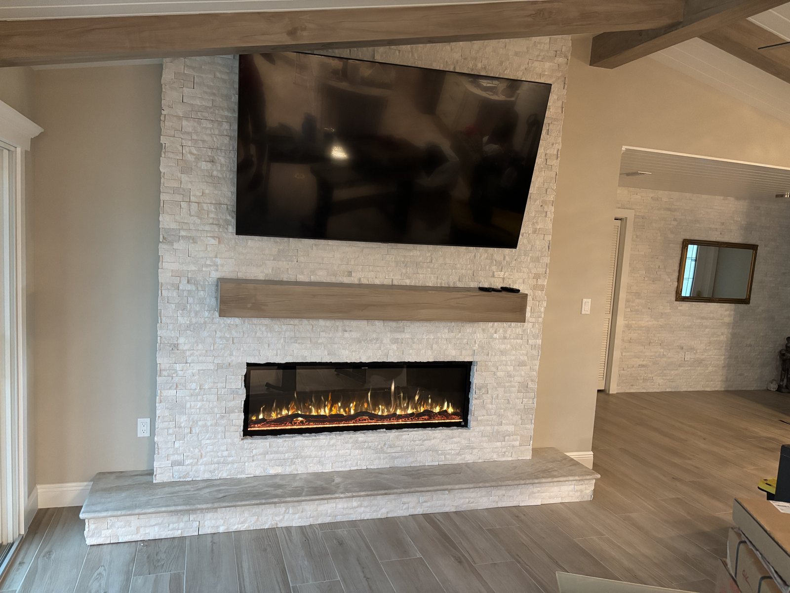 Stacked stone fireplace wall with a solid wood mantel, concealed compartment closed