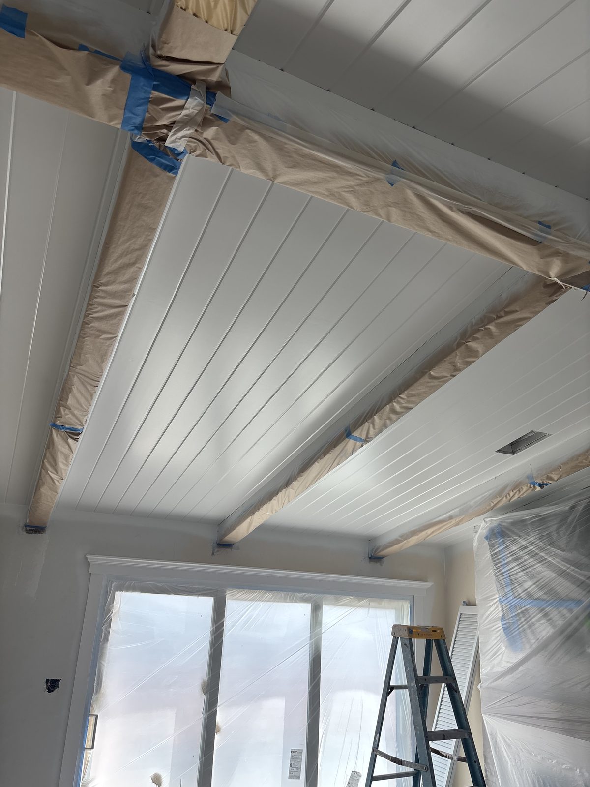White plank ceiling with painted box beams during finish work