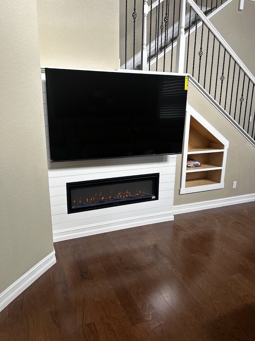 Shiplap fireplace wall with built-in shelving tucked under a staircase