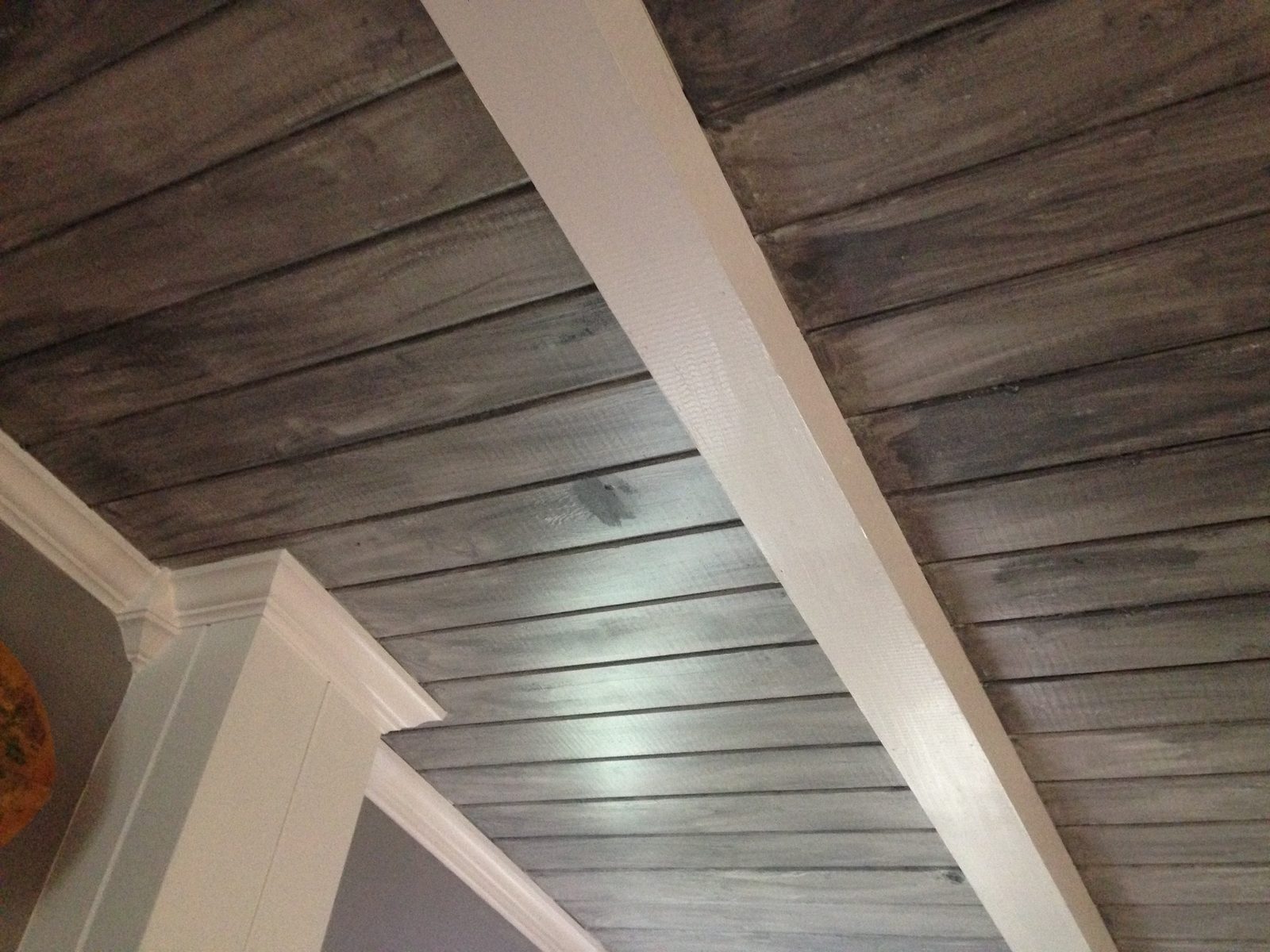 Weathered gray plank ceiling framed by painted white beams